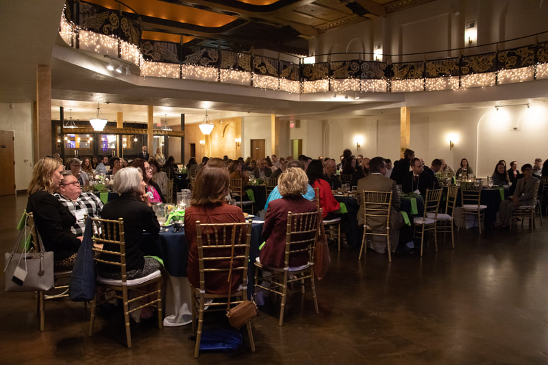 wide photo of attendees at tables 