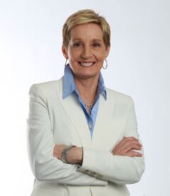 Karen Mills, white female with short blond hair in white jacket and blue shirt with collar smiling at camera