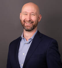 Michael Murray white man bald with a beard wearing blue shirt and black sport jacket smiling at camera